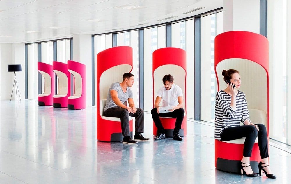 modern and colorful office reception with reds and pinks and people sitting in cocoons