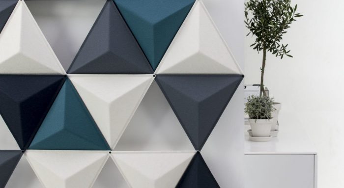 Studio shot of the Aircone acoustic panels in a pale room. This partition uses three different colors of Aircones. The Diagonal sides reveal a white platform with tall potted plants set on top.