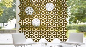 Studio shot of olive colored Airflake acoustics hung along the outer wall of the lobby. Two white chairs are placed across a glass table from one another.