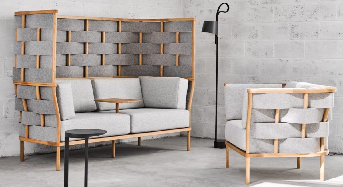 Studio shot of Bower screening in a casual seating area placed in the corner. Screening wraps a low backed chair as well as a two person couch. A small table platform comes out from the center of the couch.