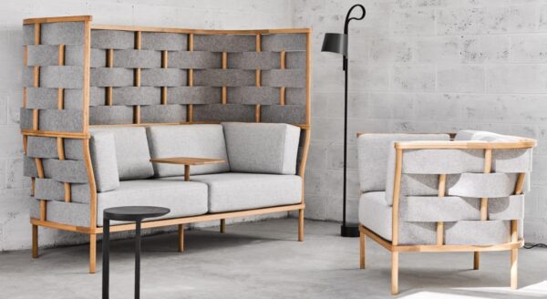 Studio shot of Bower screening in a casual seating area placed in the corner. Screening wraps a low backed chair as well as a two person couch. A small table platform comes out from the center of the couch.