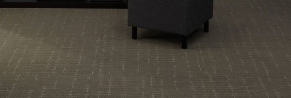 Studio shot of a cushioned ottoman resting on top of Tempo carpeting.