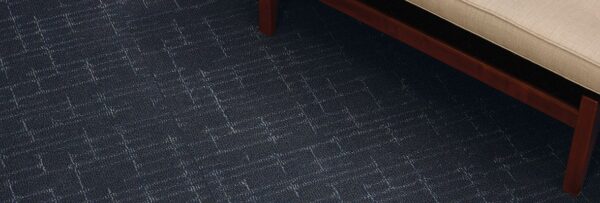 Studio shot of a wooden framed couch resting on top of Tempo carpeting.