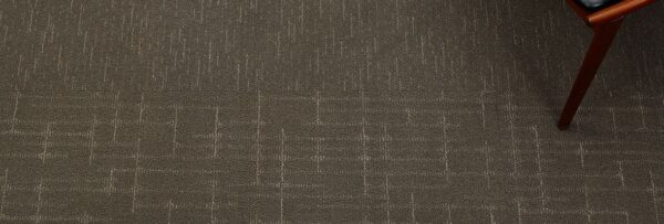 Studio shot from above of Tempo and Tone carpeting. The leg of a wooden piece of furniture marks the transition between the two.