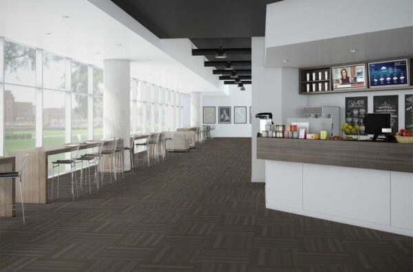 Velocity flooring inside a cafe. The counter is on one side, with two fruit bowls by the cash register. Tall backed chairs are placed in front of seating that goes all along the front window.