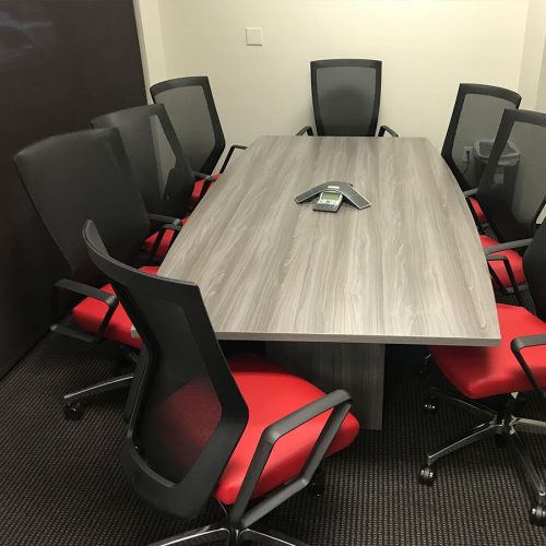 Eight Run II chairs placed at a wooden conference table. Each chair has a black mesh back and a red upholstered seat. A speaker set has been placed in the middle.